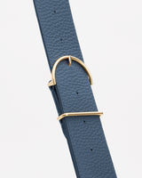 Close-up of wide strap with gold, adjustable buckle.