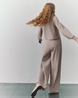 Person in a matching top and wide-leg pants standing on a tiled floor