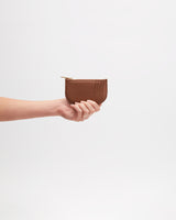 Hand holding a small pouch against a plain background.