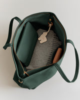 Open travel bag with a folded scarf, a wallet, and a small pouch inside.