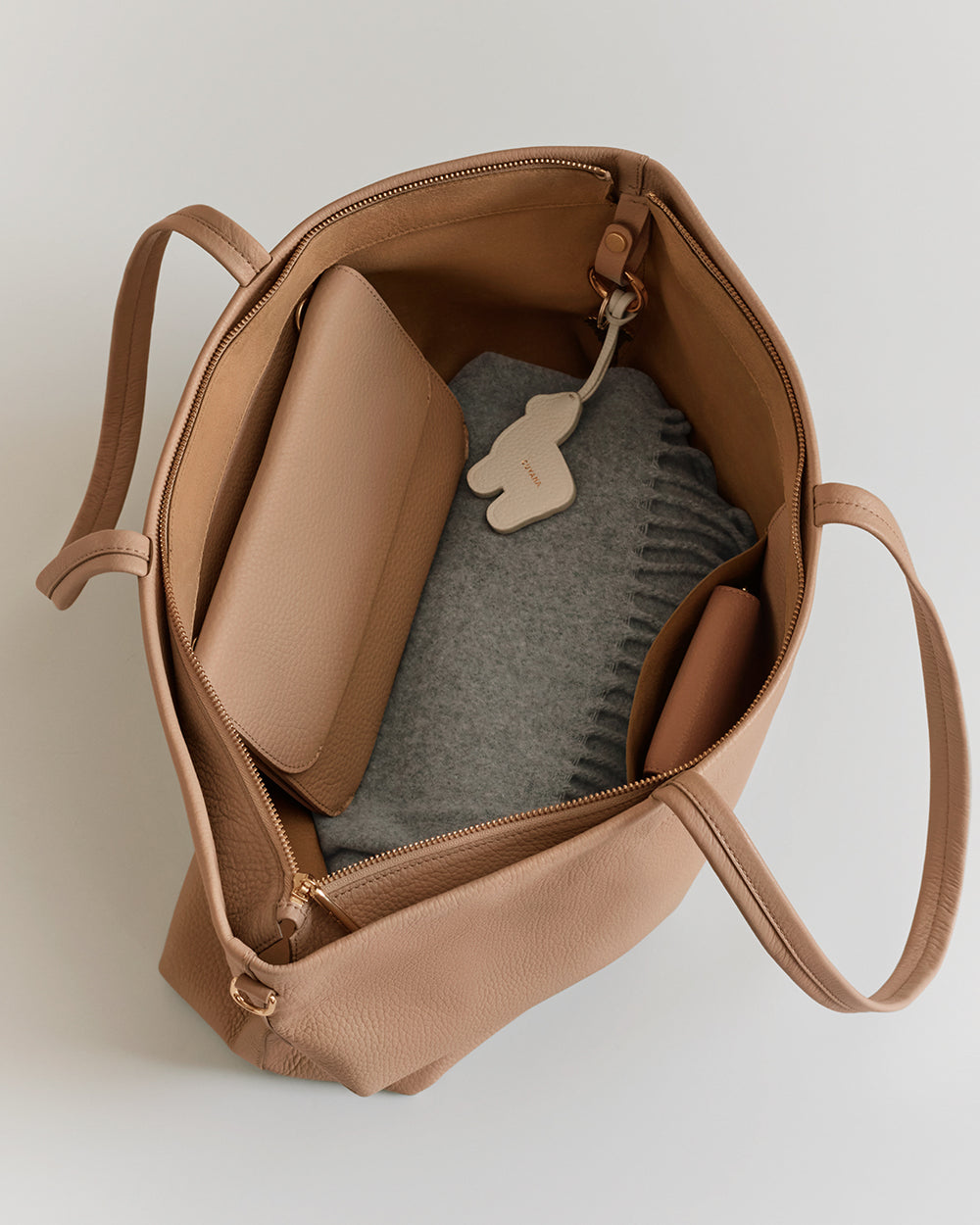 Open tote bag with a wallet, scarf, and keychain inside.
