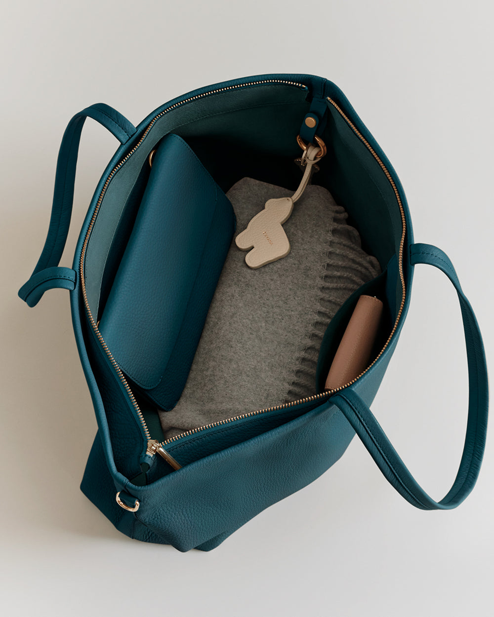 Open tote bag with a folded sweater, pouch, and a small keychain inside.