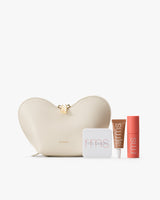 Heart-shaped pouch with three cosmetic items in tubes and compacts.