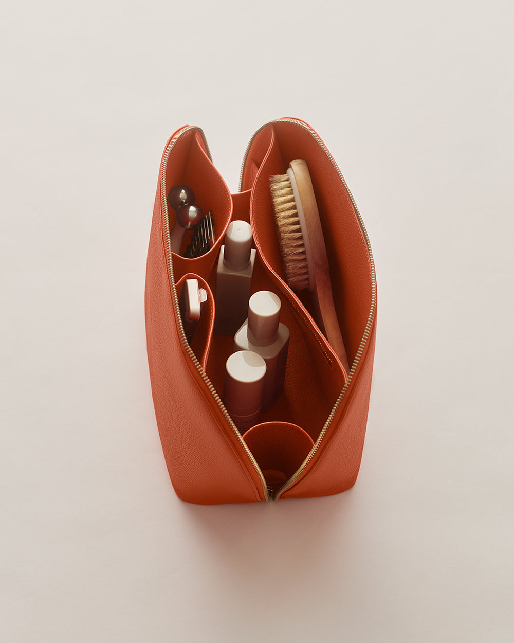 Open toiletry bag with bottles, brush, and grooming items inside.