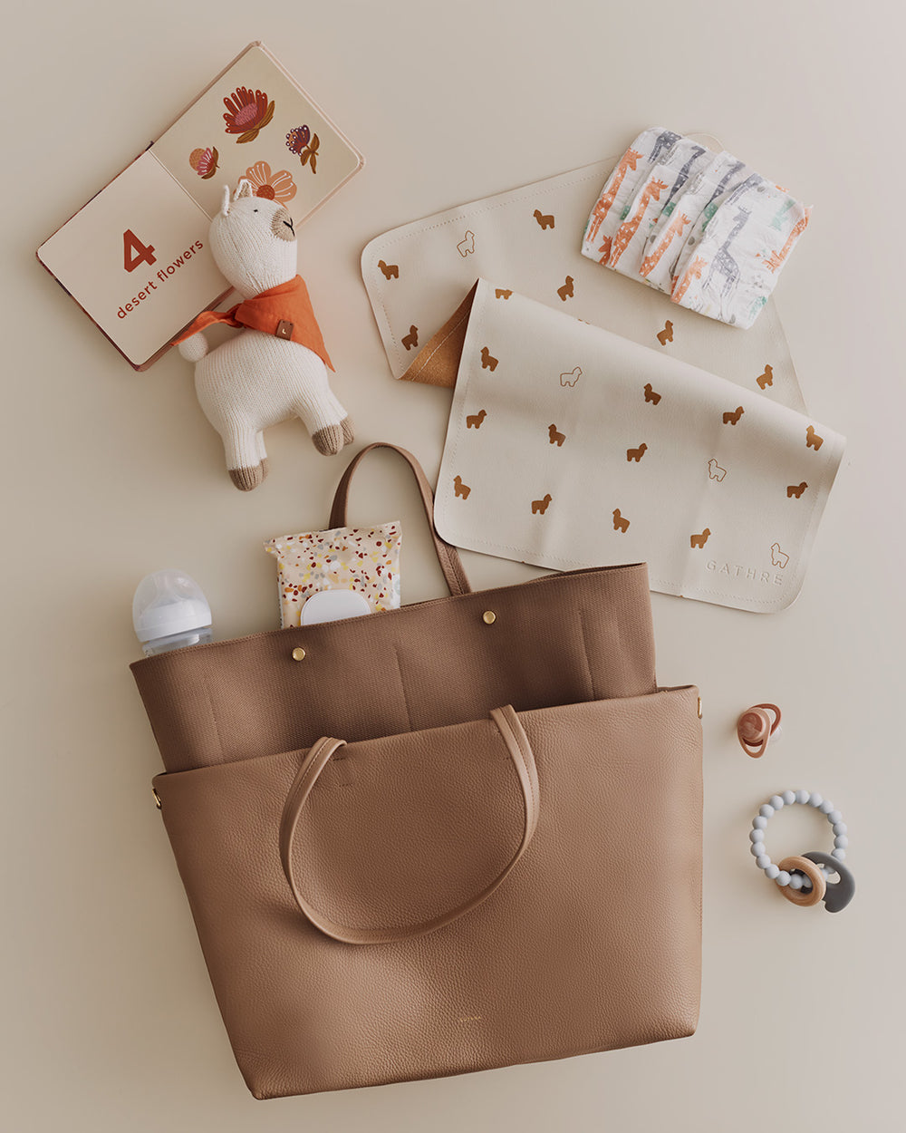 Various baby items and a large bag arranged neatly on a plain surface.