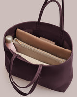 Open tote bag with a pink bottle and two zippered pouches inside.