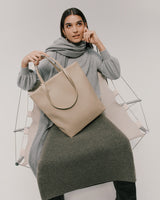 Woman sitting in a clear chair holding a large bag.