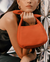 Person holding a handbag with shiny background.