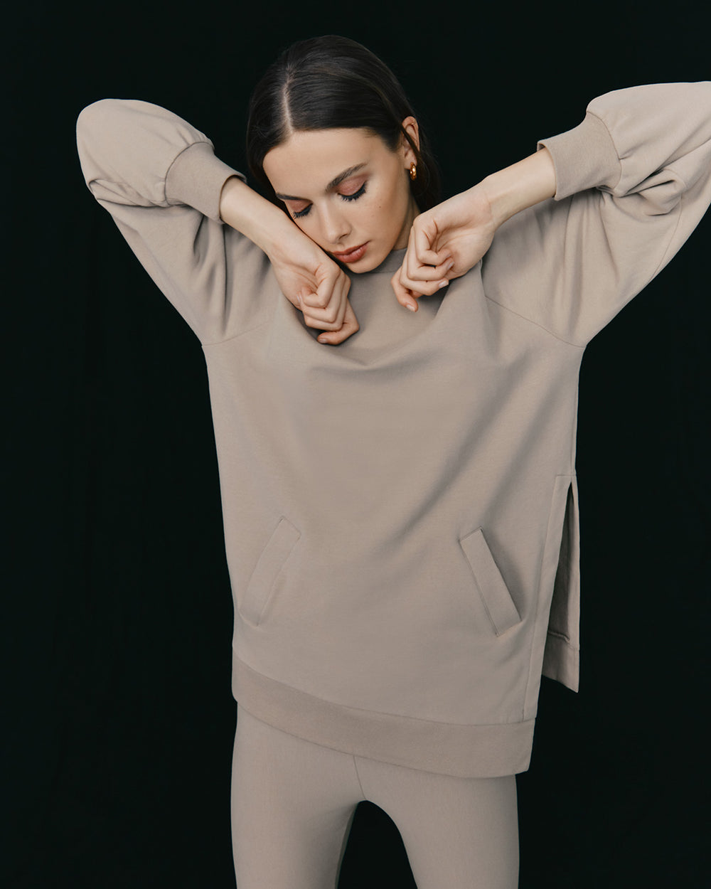 Woman posing with her hands resting on her head and elbows out.