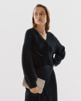 Woman standing with one hand on hip, looking to the side.