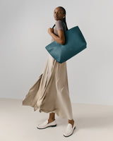 Person holding a large tote bag, wearing a long skirt and loafers