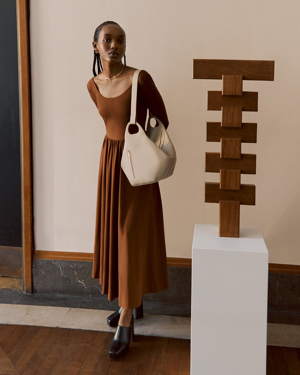 Woman standing next to a sculpture on a pedestal in a room.