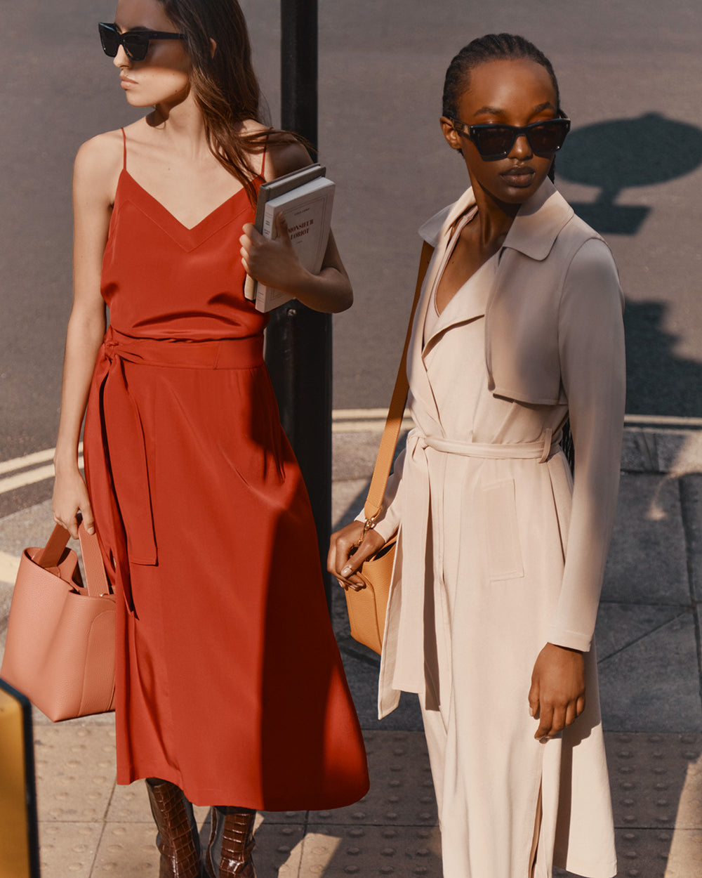 Two women walking on a street, one holding a coffee cup.