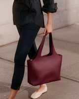 Person walking, carrying a large tote bag over their shoulder.