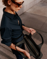 Woman holding an open handbag on a city sidewalk.