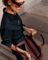 Person wearing sunglasses, holding an open tote bag.