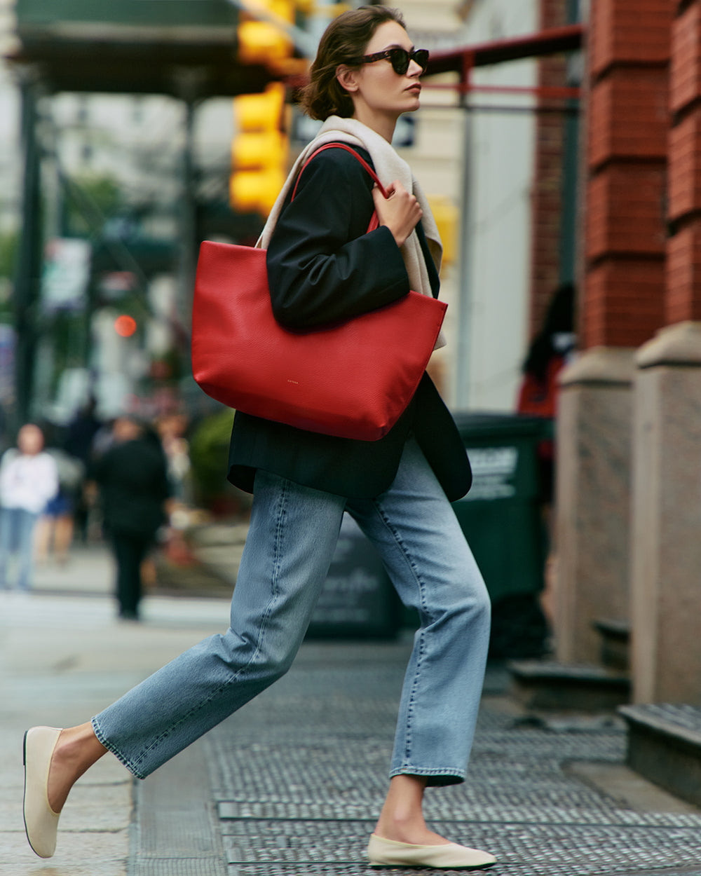 Person walking on a city street carrying a large tote bag