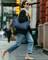 Person walking on the street with a large bag over their shoulder.