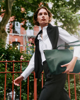 Person walking with large handbag in urban setting.