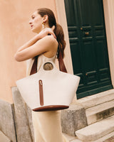 Person standing outside holding a large tote bag