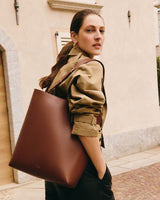 Person standing outside holding large tote bag over shoulder