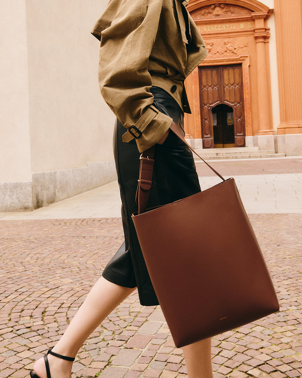 Person walking outdoors carrying a tote bag