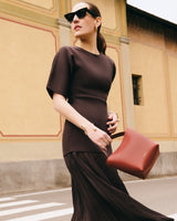 Person in dress with handbag and sunglasses walking near building