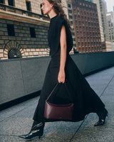 Woman walking on city sidewalk holding handbag