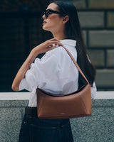 Person wearing sunglasses and carrying a shoulder bag.