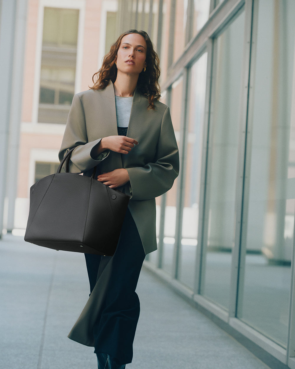 Person walking indoors carrying large handbag