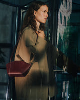 Person standing by glass door with shoulder bag.