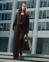 Person wearing suit with top walking down steps holding a tote bag in city setting