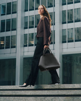 Person walking on steps holding a large handbag in front of a building