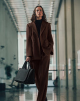 Person in suit holding a handbag walking in a building corridor.