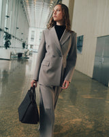 Person in suit holding handbag walking in spacious hall with modern design.