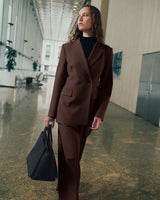 Person in a suit carrying a bag walking in a spacious hallway.