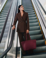 Person in suit holding a tote bag on an escalator.