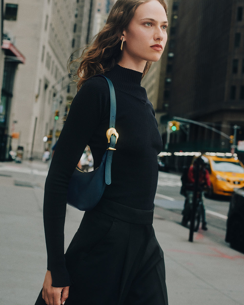 Woman walking on city street holding a shoulder bag