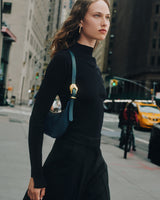 Woman walking on city street holding a shoulder bag