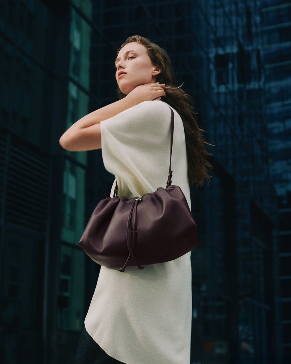 Person standing in city, carrying a shoulder bag over their arm.
