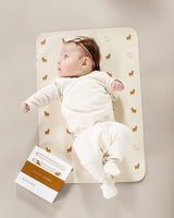 Baby lying on a mat next to a book.