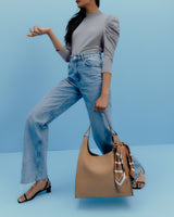 Person in casual outfit holding a handbag with scarf accent.