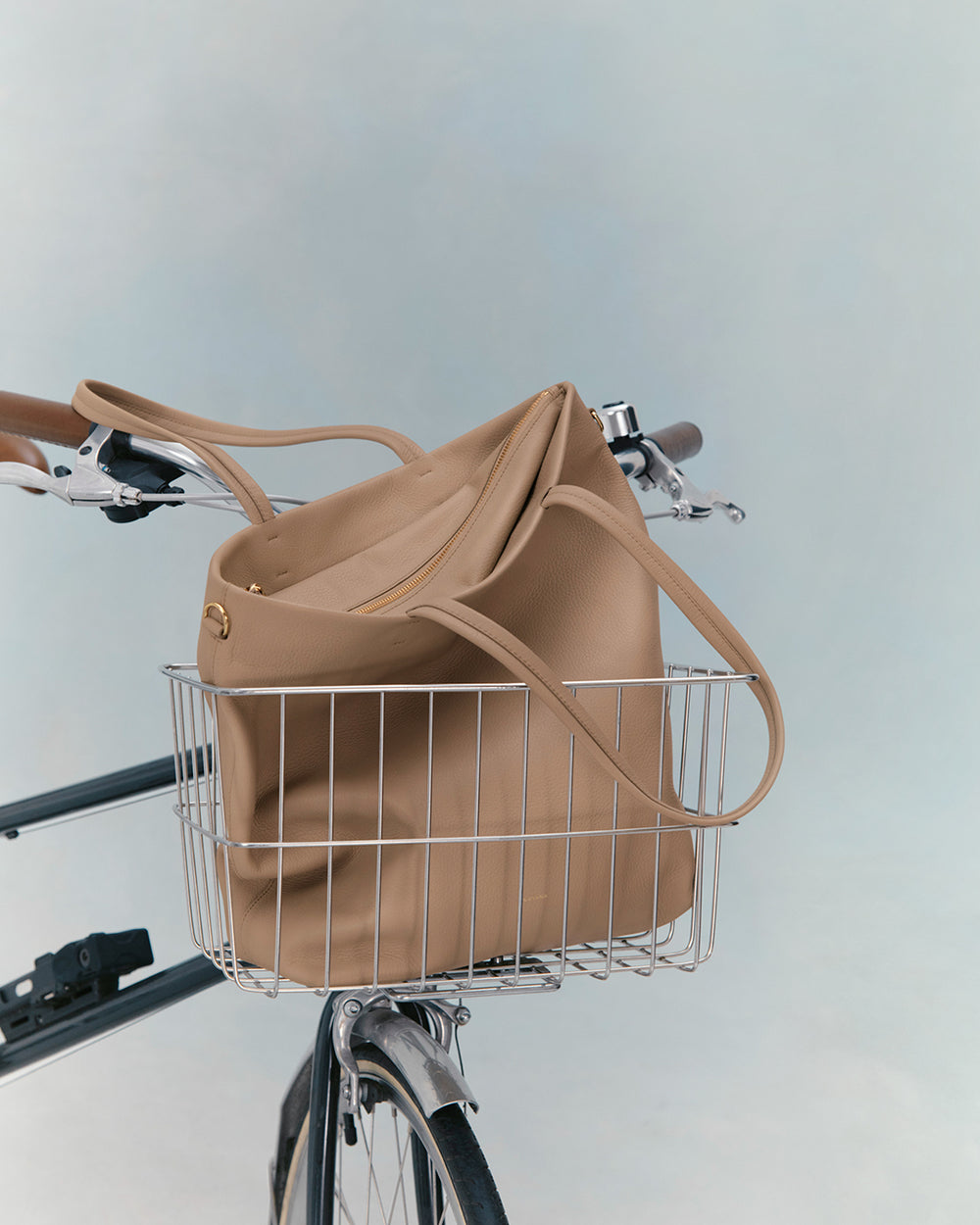 A tote bag in the front basket of a bicycle