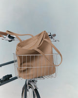 A tote bag in the front basket of a bicycle