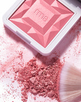 Blush powder with brush beside a compact case.
