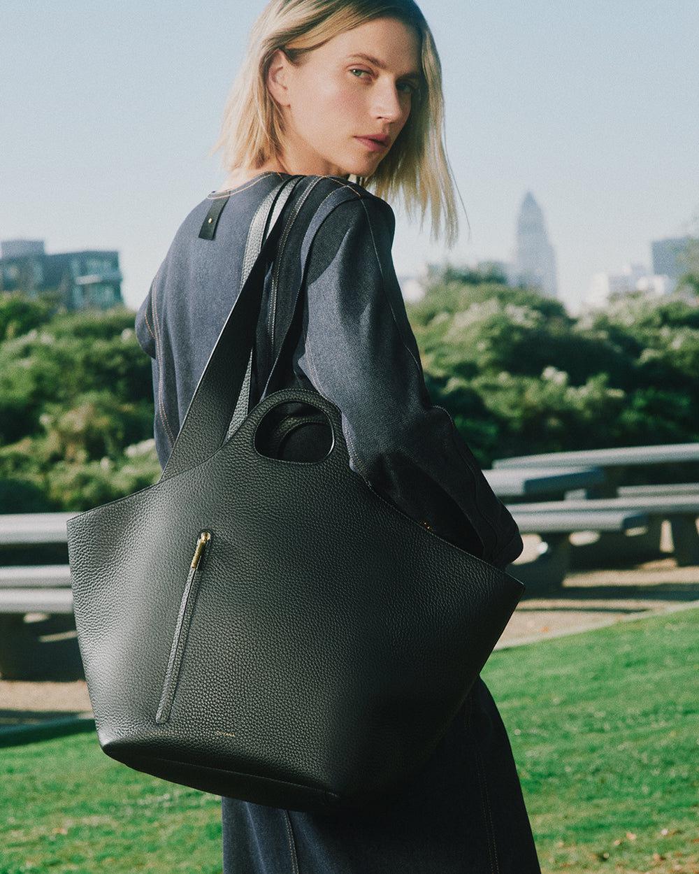 Person outdoors holding a large tote bag over their shoulder.