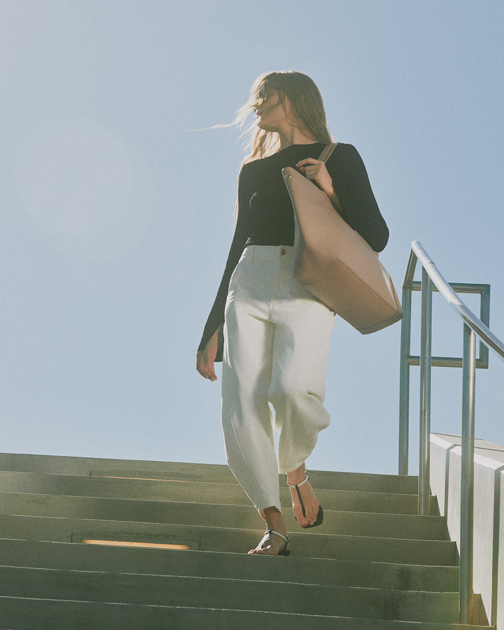 Person walking down steps carrying a large tote bag