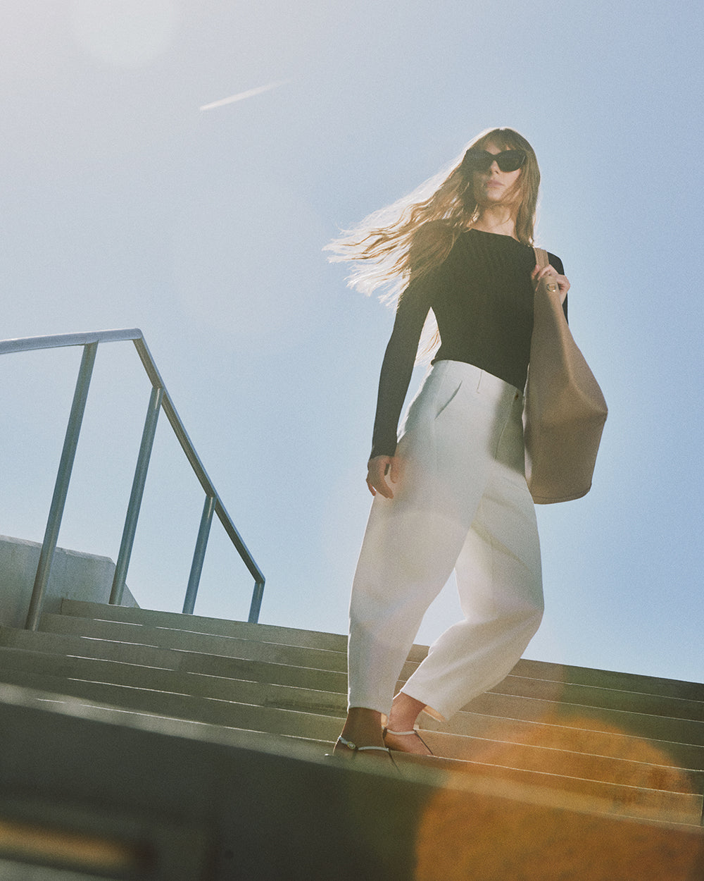 Person on stairs wearing sunglasses and holding a large bag