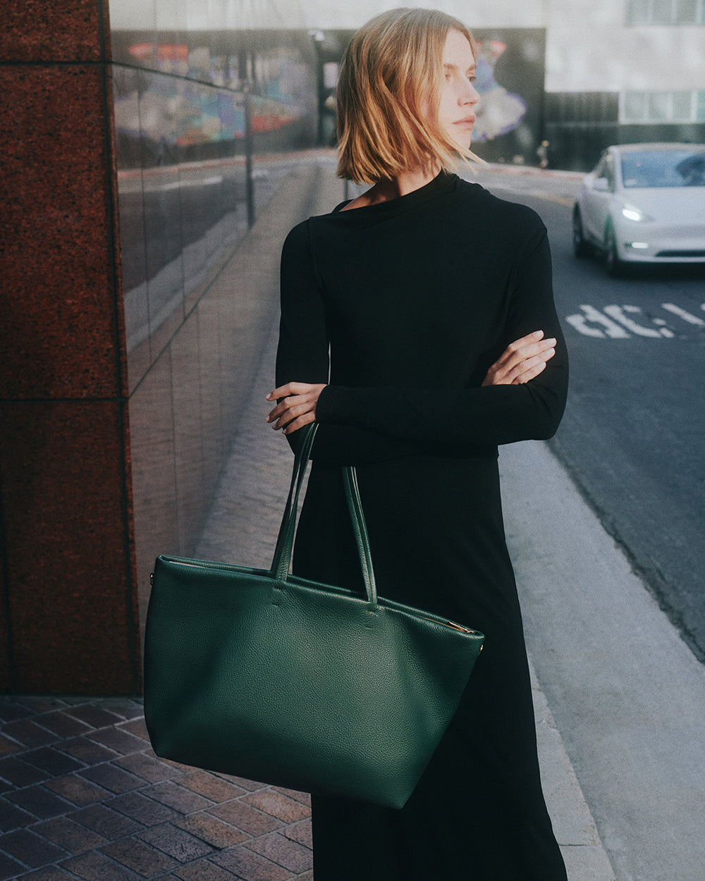 Person holding a large handbag while standing on a city street.