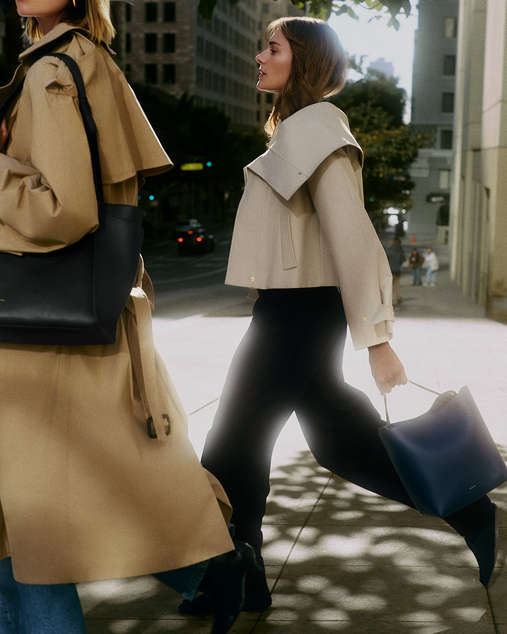 Two people walking on a city street, one holding a handbag.